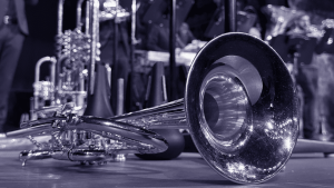 A brass trumpet on stage with musicians in the background.